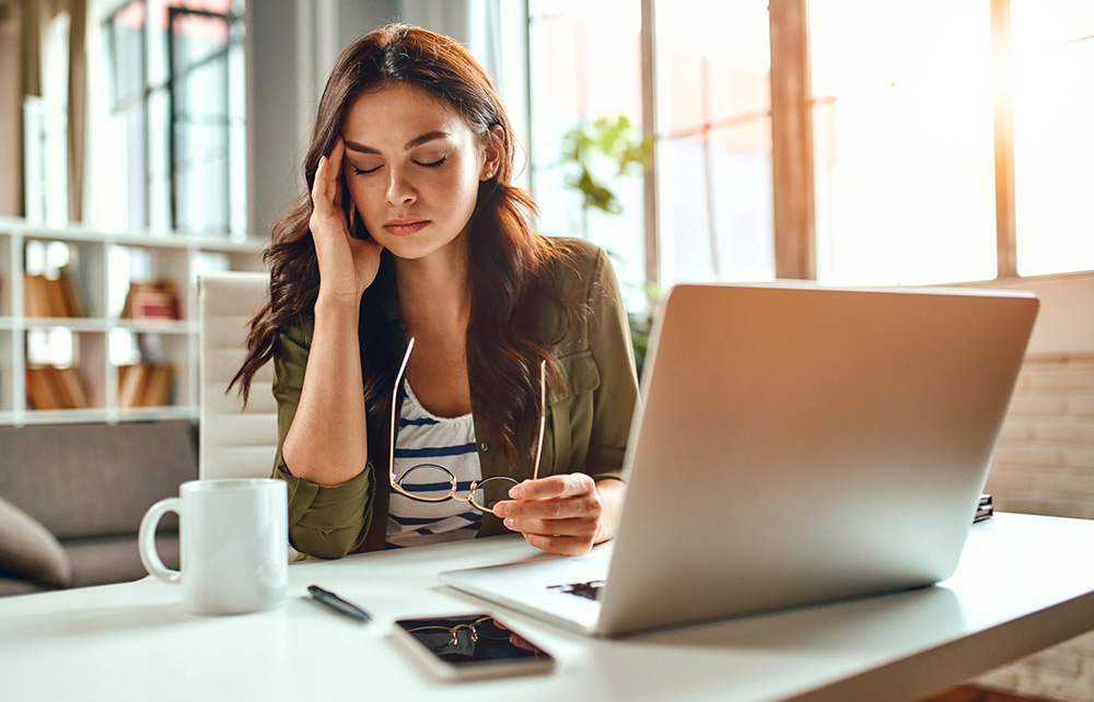 A woman at her desk, looking tired.