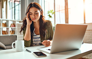 A woman at her desk, looking tired.