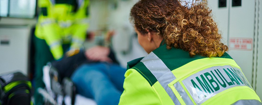 Two paramedics move a patient on a stretcher into an ambulance.
