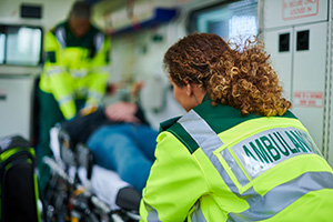 Two paramedics move a patient on a stretcher into an ambulance.