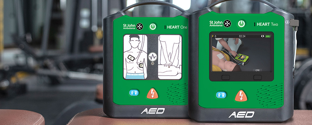The St John Ambulance HEART One and HEART Two defibrillators on a table inside of a gym.