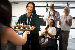 A group of office workers presenting a birthday cake to their colleague.